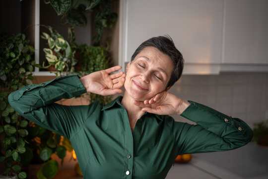 Happy senior woman in kitchen smiling and stretching. Glad female quiet start to day, weekend relaxation at home, personal time positive emotion, slow life after retirement, self care and hygge