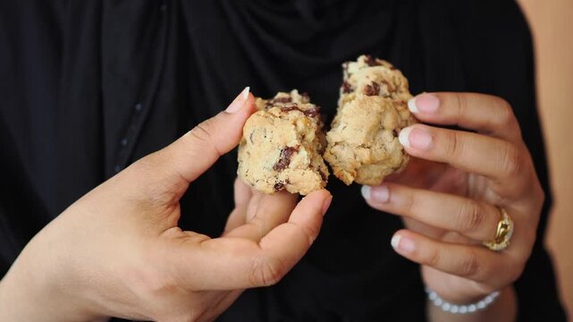 A person breaks apart a cookie in a bakery. Fresh cookies are served