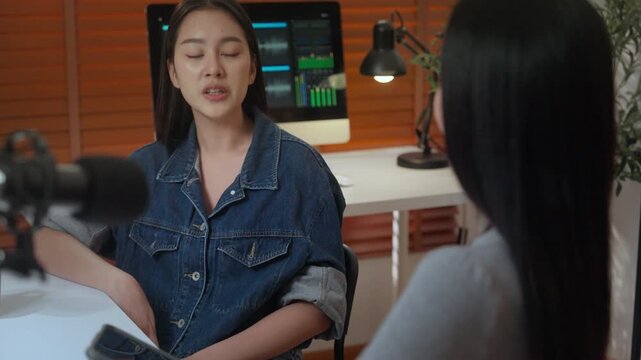 Podcast digital creator home studio recording with microphone, conversation and interview between woman and guest, calm workspace, warm light, screen waveform, coffee cup, focused audio creation