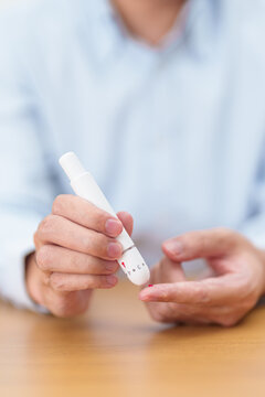 Hand using lancet pen on finger with Blood drop glucose testing or Diabetes checking by digital blood glucose meter. blood sugar level, Diabetes Day, Glycemia, Hypoglycemia, Hyperglycemia and insulin