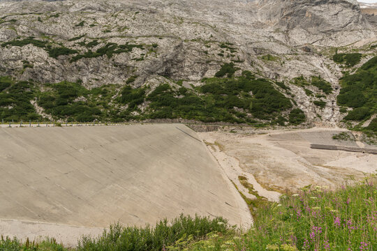 Canazei, Italy. Lago di Fedaia reservoir dam and exposed lakebed showing drought and low water levels in the Dolomites