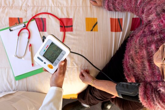 Top View Doctor checking an older woman's blood pressure at home
