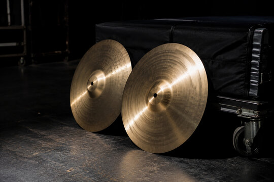 Polished orchestral cymbals leaning against padded cart backstage, music equipment and performance preparation concept