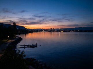 Naklejka premium Serene Twilight Over a Coastal City with Calm Water and Distant Lights.
