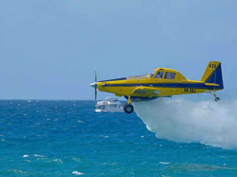 Yellow Firefighting Aircraft Releasing Water Over the Ocean in Gold Coast