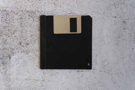 Close-up of an old floppy disk against a rough concrete background