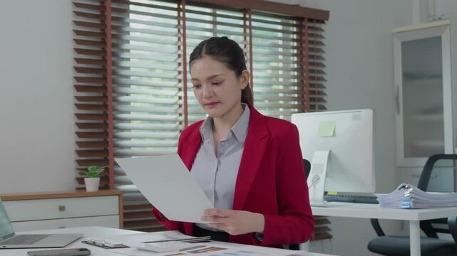 Young businesswoman reading financial report document at her office desk