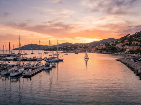 Serene Harbor at Sunset with Sailboats and Coastal Town.