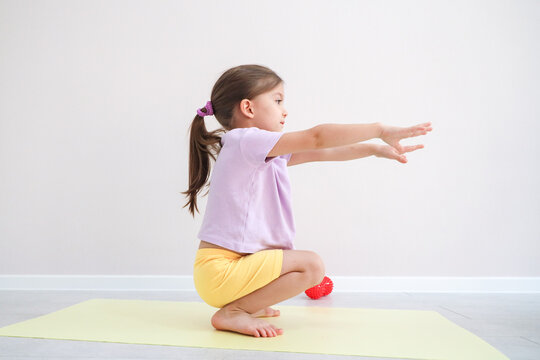Side View Of Young Girl In Yoga Balance Pose With Arms Stretched Forward On Pale Mat In Bright Minimal Room, Showing Focused Movement, Flexibility, Indoor Exercise, Healthy Habits