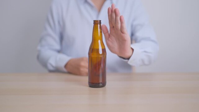 man making stop hand gesture to refuse a bottle of Beer, Healthy man say no to alcohol drink, stop alcoholism and addiction concept. Responsible man reject a drink before driving and quit booze