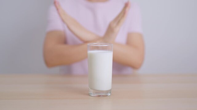 Lactose intolerance and Milk allergy. woman hand stop and refuse Milk, having abdominal cramps and pain when drink Cow Milk. Symptom stomach ache, Dairy intolerant, Nausea, Bloating, Gas and Diarrhea