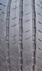 ​Close-up macro texture of a worn car tire tread showing grooves and sipes © I
