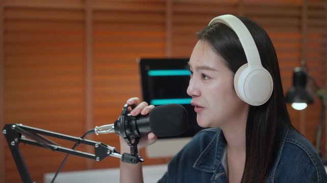 Podcast digital creator home studio microphone headphone woman recording clear audio, focused voice at desk, warm lamp light, wood blind backdrop, cozy modern workspace, calm talk, smiling