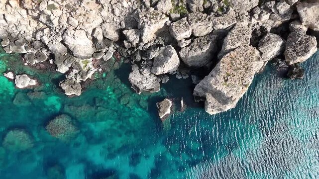 jagged limestone rock outcrops malta turquoise sea reef patterns birds eye drone shot clear water rugged coastal texture erosion natural mediterranean