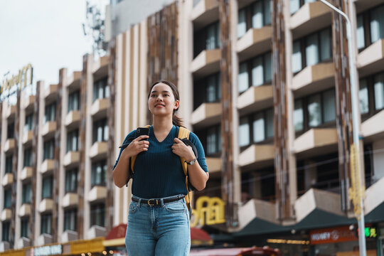 Young woman traveling exploring urban city street with backpack