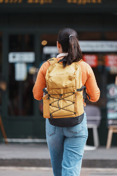 Woman walking urban street with yellow backpack