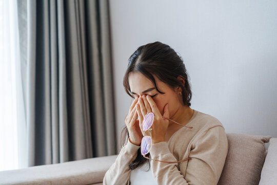 Young woman rubbing her eyes from using eyesight to relieve eye pain after using mobile phone