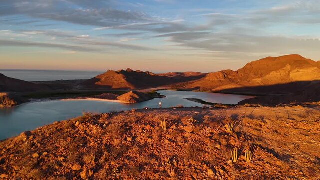 Revealing aerial shot of desert hilltop overlook at sunset facing Balandra bay in La Paz Mexico