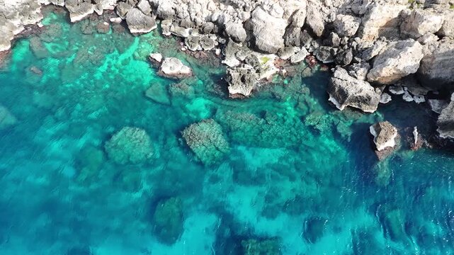 turquoise water submerged limestone reef malta coastline aerial drone footage clear shallow sea rocky shoreline mediterranean cliffs natural cove crystal clarity underwater rock texture coastal