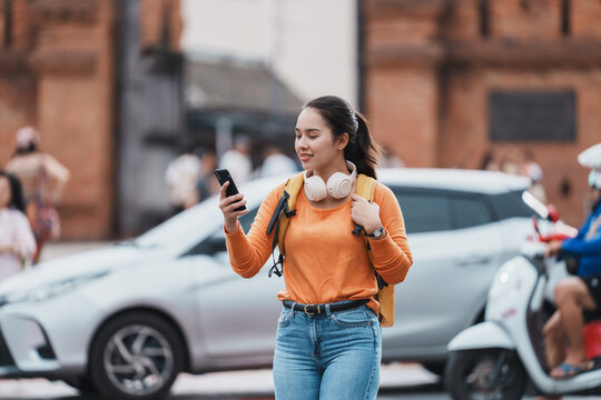 Young asian woman traveler navigating city street with phone