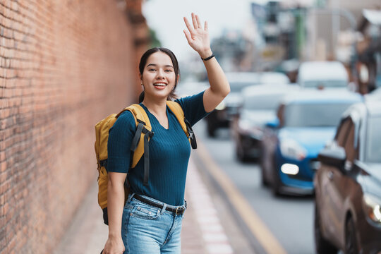 Traveler woman waving hand stopping taxi in city