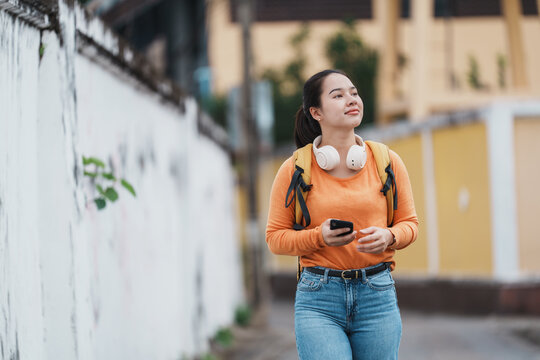 Young woman walking urban street holding smartphone