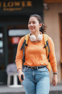 Young woman walking city street with headphones