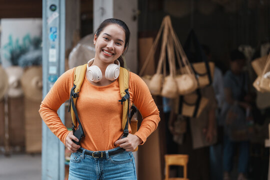 Asian woman traveler smiling wearing backpack and headphones