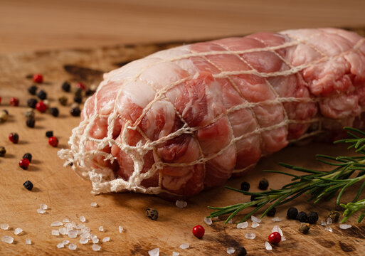 Macro Close Up of Raw Pork Shoulder Roast Tied in Meat Netting on Wooden Cutting Board