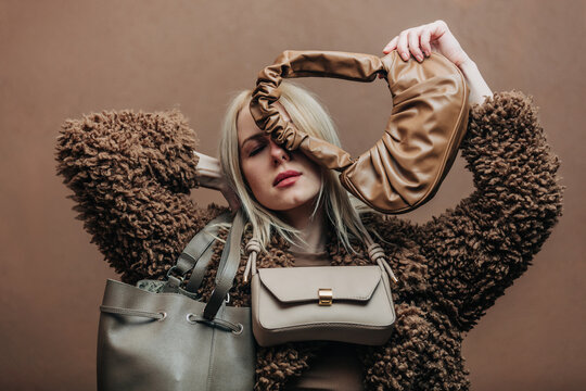 A stylish blonde woman wearing a teddy coat paired with vintage bags, standing against a rich brown background in shade Mocha Mousse