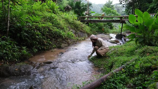A woman touching and playing with water in the creek