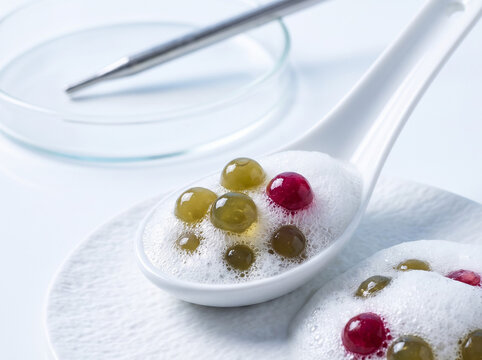 Molecular gastronomy modernist spherification fruit caviar pearls with airy culinary foam on spoon
