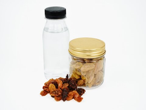 Dried raisins and water isolated white background closeup