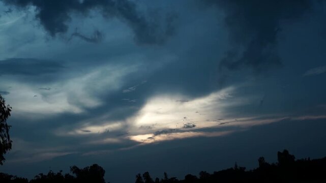 Cinematic dusk sky background with soft sunlight breaking through heavy overcast clouds