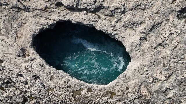 blowhole interior malta coral lagoon overhead drone shot swirling turquoise water limestone rock rim close up natural sinkhole texture pattern karst erosion mediterranean rock formation dramatic