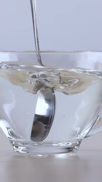 Metal Spoon Stirring Hot Water in Transparent Glass Cup