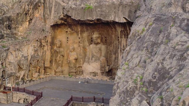 Aerial view of monumental Vairocana Buddha, Longmen Grottoes, UNESCO heritage site in Luoyang, China。Ancient Buddhist rock‑cut statues, Longmen Grottoes, traces of iconoclasm and cultural looting