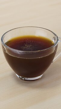 Pouring Instant Coffee Powder into a Glass Cup of Hot Water
