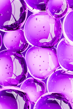 Abstract 3D composition of glossy purple bubbles and transparent spheres with liquid droplets. Futuristic beauty, skincare, hydration, collagen and biotechnology concept with a vibrant background.