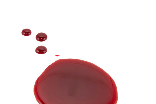 Large red liquid puddle with several smaller droplets scattered on a plain white surface isolated on a transparent background