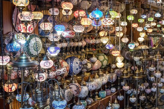 Rows of colorful mosaic glass lamps hang densely in traditional Turkish shop, illuminated with warm glow