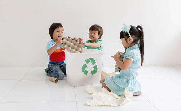 Three young asian caucasian children sorting household waste into a recycling box, learning environmental responsibility through teamwork and playful leisure activity.