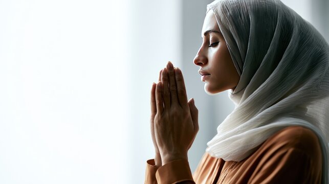 Woman wearing hijab praying with eyes closed