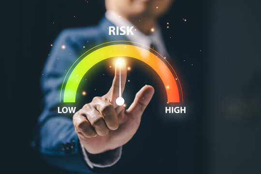 Business risk management concept with professional selecting a virtual risk gauge from low to high, representing assessment, uncertainty, decision making and corporate strategy planning.