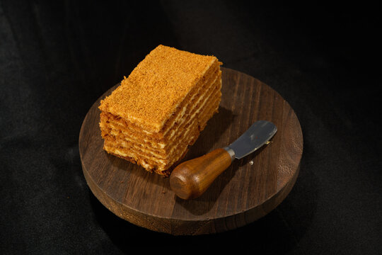 serving of layered cream cake on a wooden stand with a serving knife