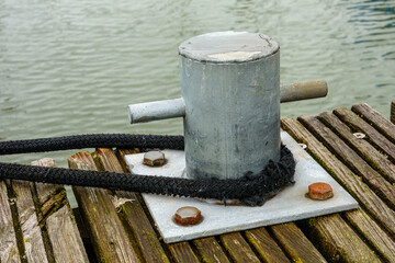 Metal bollard securing boat with rope on wooden pier © jokuephotography