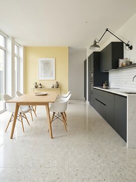 Bright modern kitchen and dining room with dark grey cabinets, yellow accent wall, wooden table and terrazzo tile flooring