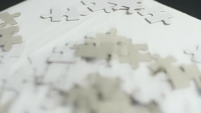 Cinematic macro shot of scattered white puzzle pieces on clean surface featuring smooth camera motion and soft lighting.