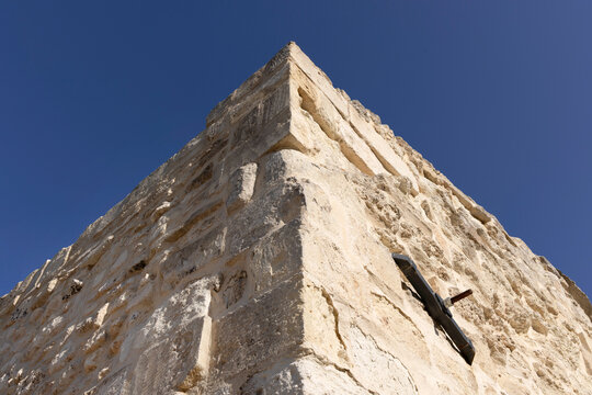 Muro in pietra ad angolo con capochiave sulla parete destra e sfondo cielo
