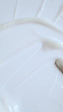 Cosmetic spatula smearing white cream creating smooth and delicate texture in macro view